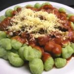 Green spinach gnocchi with tomato sauce and grated parmesan