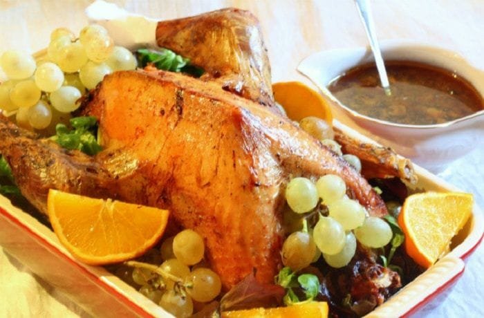 Roast stuffed Christmas turkey decorated with grapes, oranges, and apples