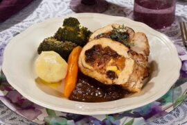 Roast turkey breast stuffed with ham and apples, sliced and served with sauce