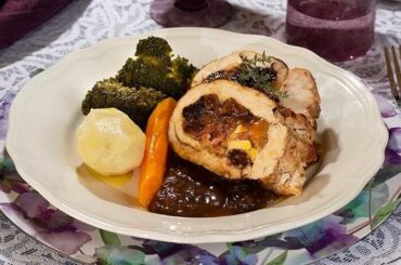 Roast turkey breast stuffed with ham and apples, sliced and served with sauce