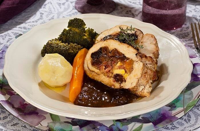 Roast turkey breast stuffed with ham and apples, sliced and served with sauce